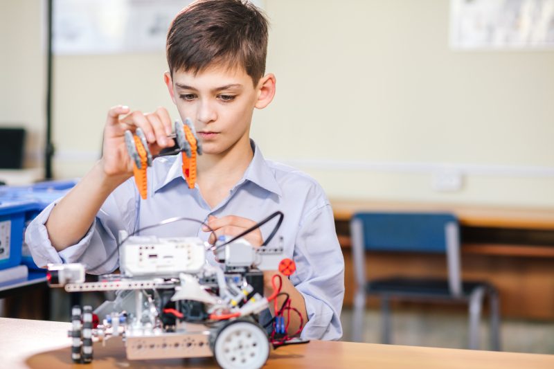 Little boy in robotics school makes robot